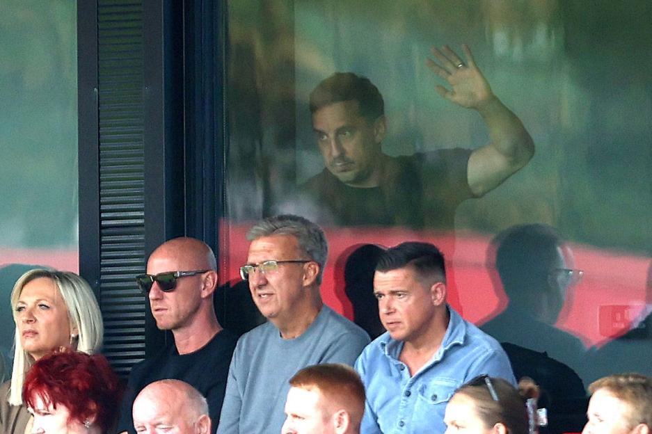 Gary Neville waving from a box at a Salford City football match.