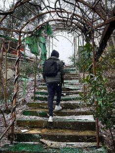 Person walking up snowy stairs in an abandoned theme park.