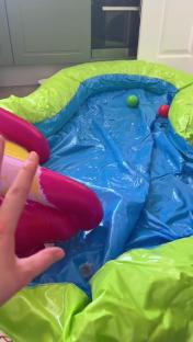 Inflatable paddling pool with a slide and two small balls inside.
