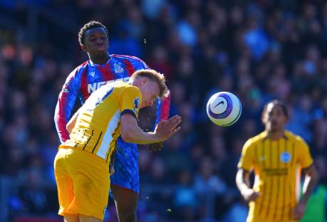 Soccer player in yellow jersey heads the ball.