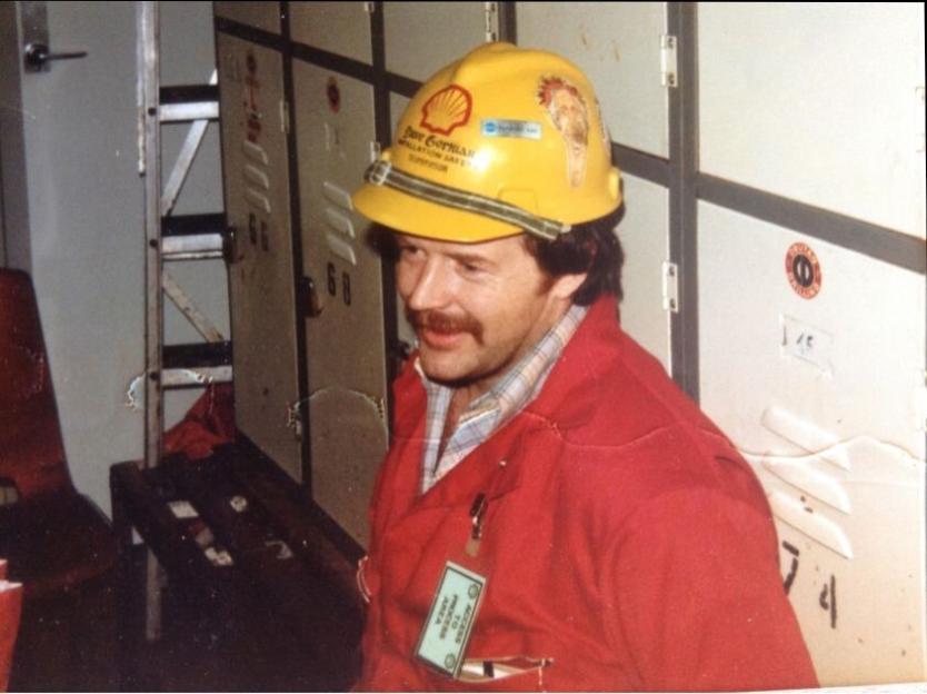 Photo of Dave Gorman in a yellow hard hat and red jacket.