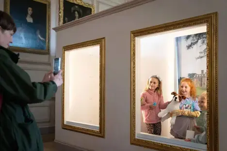 Person photographing children in ornate picture frames.