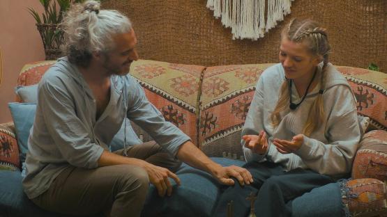 A man and woman sitting on a couch and talking.