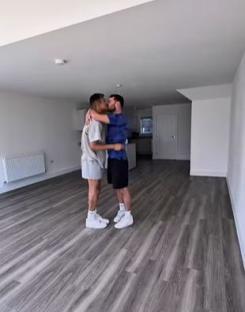 Two men kissing in a new home.