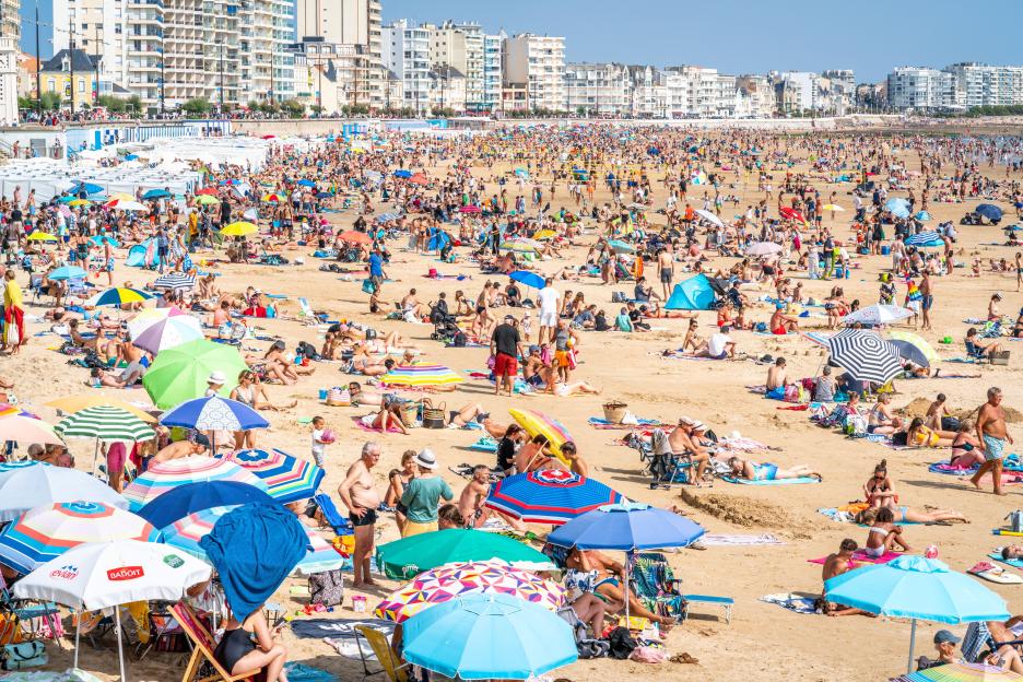 Crowded beach with many people under umbrellas.