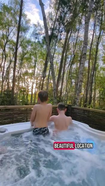 Two boys in a hot tub surrounded by trees.