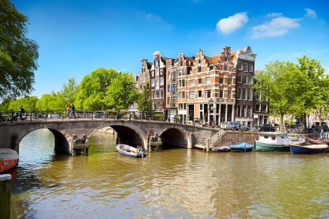 Amsterdam canal scene with boats and traditional buildings.