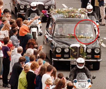 Funeral procession with mourners lining the street.