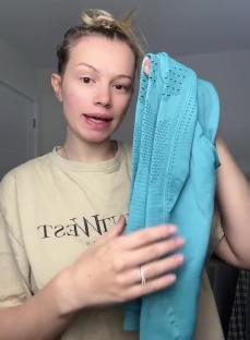 Person holding up teal clothing items.