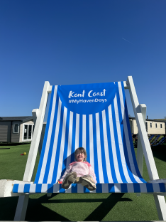 Child sitting in oversized beach chair on Kent Coast.