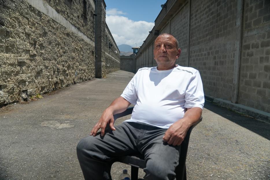 A man sits in a chair in the courtyard of La Picota Prison.