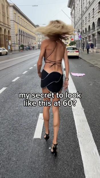 Woman in a short black dress walking down a city street.