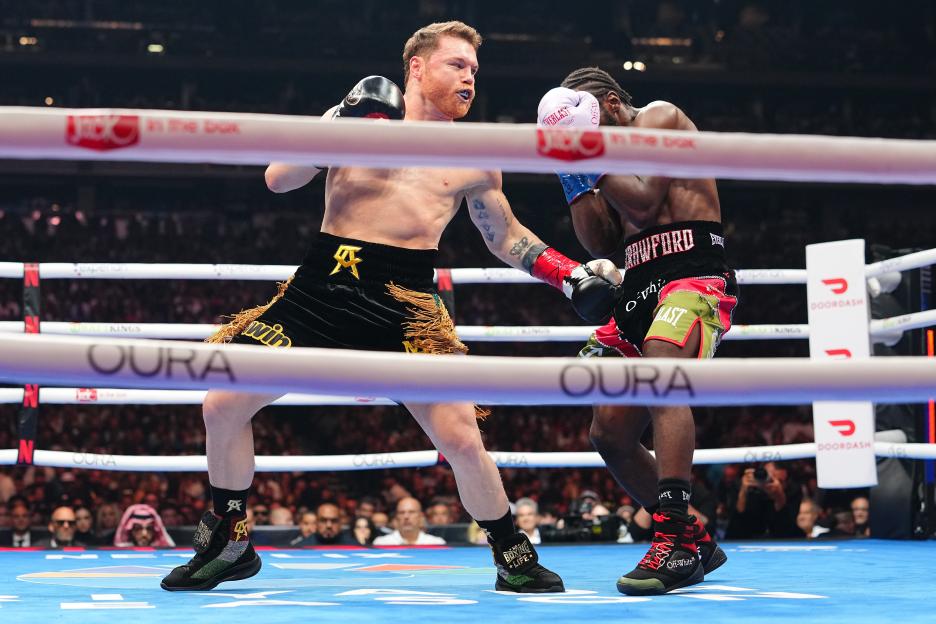 Canelo Alvarez (red gloves) punches Terence Crawford during a boxing match.