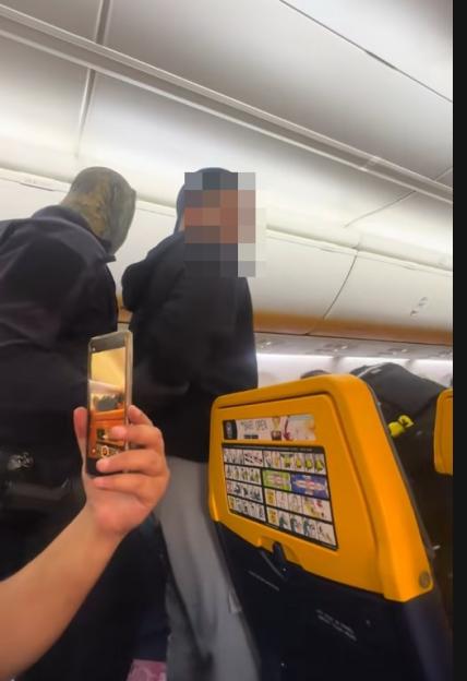 A person records two blurred passengers on a Ryanair flight.