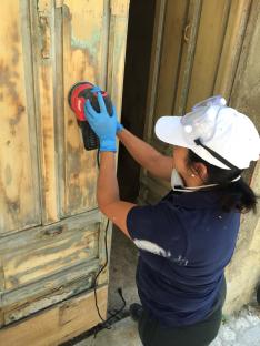 Woman sanding a door.