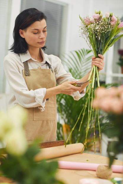 A florist trimming the stems of a bouquet.