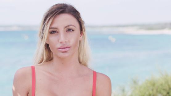 Woman in a red bikini top against a beach background.