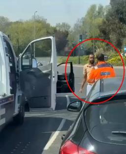 Video still of a road rage incident: a man in a beige shirt punches a recovery truck driver in an orange jacket.