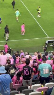 Lionel Messi walking down a soccer field tunnel, with fans in the stands.