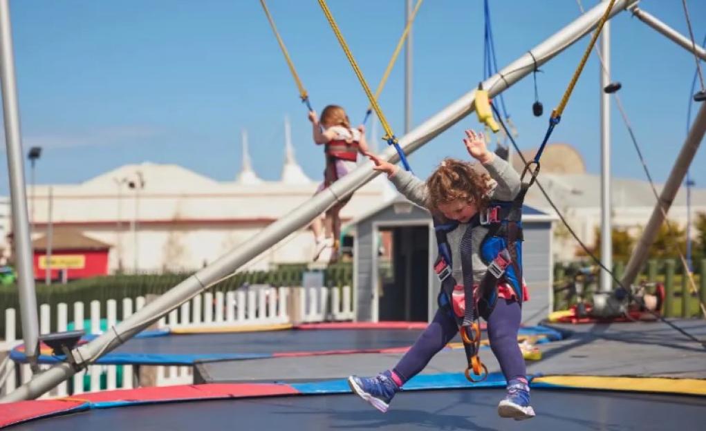 Two children bouncing on a trampoline.
