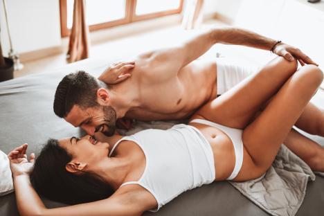 Couple embracing and kissing in bed.