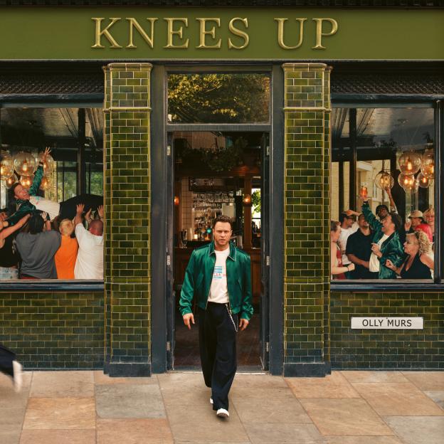 Olly Murs exits the "Knees Up" pub as people party inside.