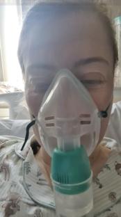 Woman in hospital bed using a breathing mask.