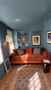 Graham Norton's New York townhouse living room with an orange couch, bookshelves, and artwork.