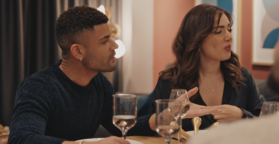 A man and a woman talking at a table with wine glasses.