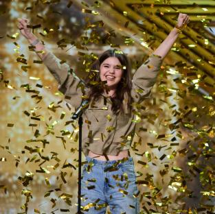 A woman celebrates amidst falling gold confetti.