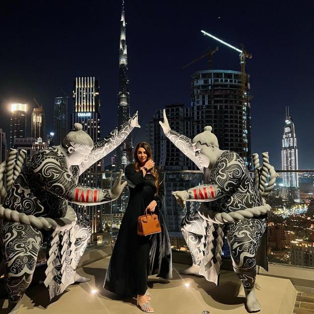 a woman stands in front of a statue of a sumo wrestler