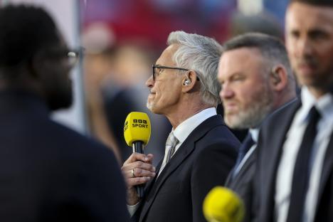 Man in suit and glasses speaking on television.