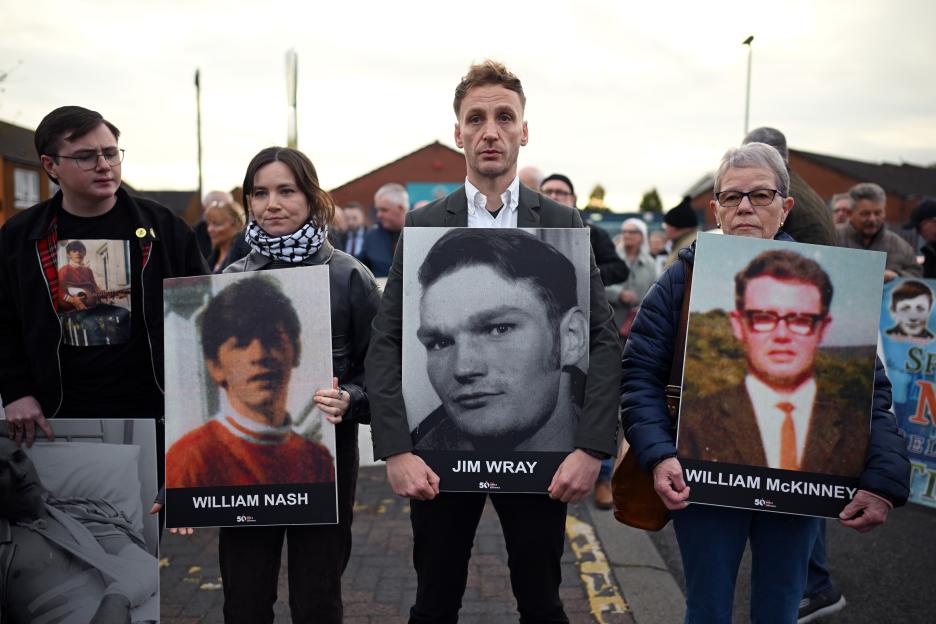 People holding images of murder victims William Nash, Jim Wray, and William McKinney at a rally.