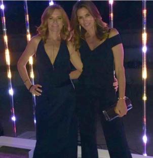 Two women in black jumpsuits posing together.