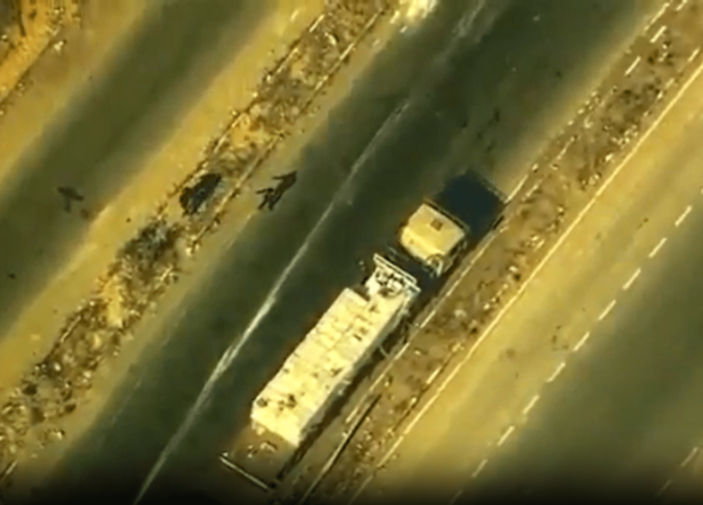 Aerial view of a cargo truck on a highway next to debris and possible bodies.