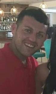 Close-up photo of a smiling man wearing a red shirt.