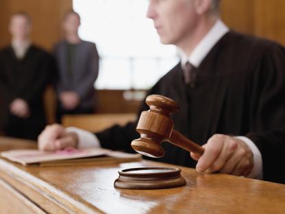 Judge holding a gavel in a courtroom.
