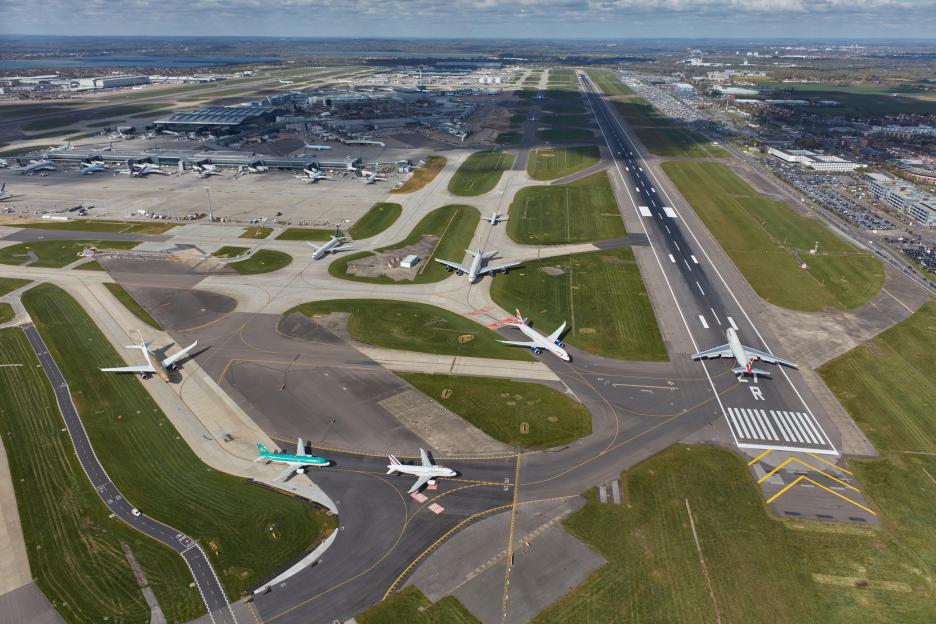 Aerial view of Heathrow Airport showing runways, taxiways, terminals, and parked aircraft.