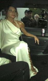 Victoria Beckham in a light-colored dress in a car.