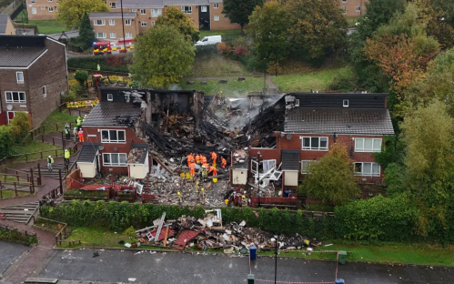 Aerial view of a fire-damaged building with emergency personnel on site.