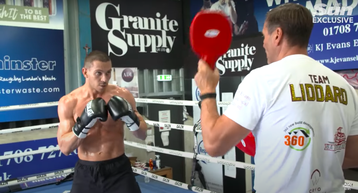 Boxer training with a coach using a paddle.