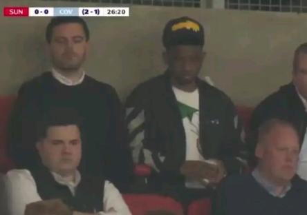 Screenshot of people sitting in stadium seats.