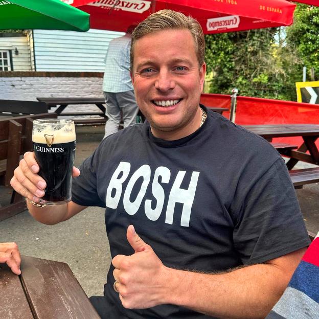 Man holding a Guinness pint and giving a thumbs up at a pub.