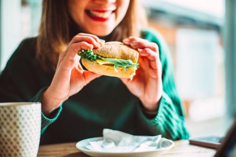 Businesswoman eating a veggie burger during a lunch break.
