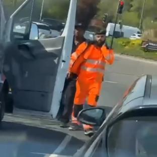 A recovery truck driver in an orange jacket walks away after a road rage incident.
