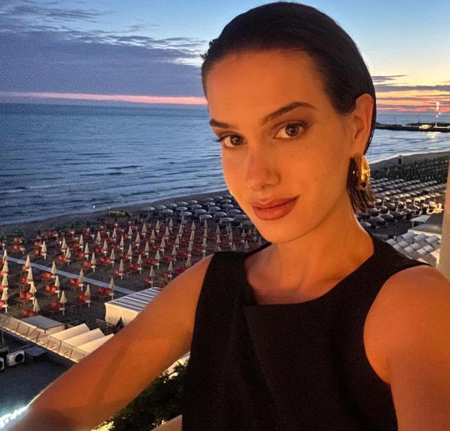 Noelle posing in front of a beach at sunset.