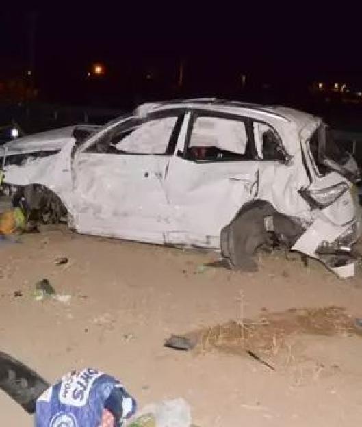 A wrecked car on the side of a road at night.