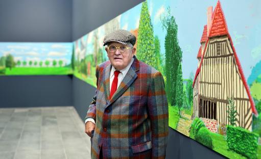 David Hockney standing in front of his painting,