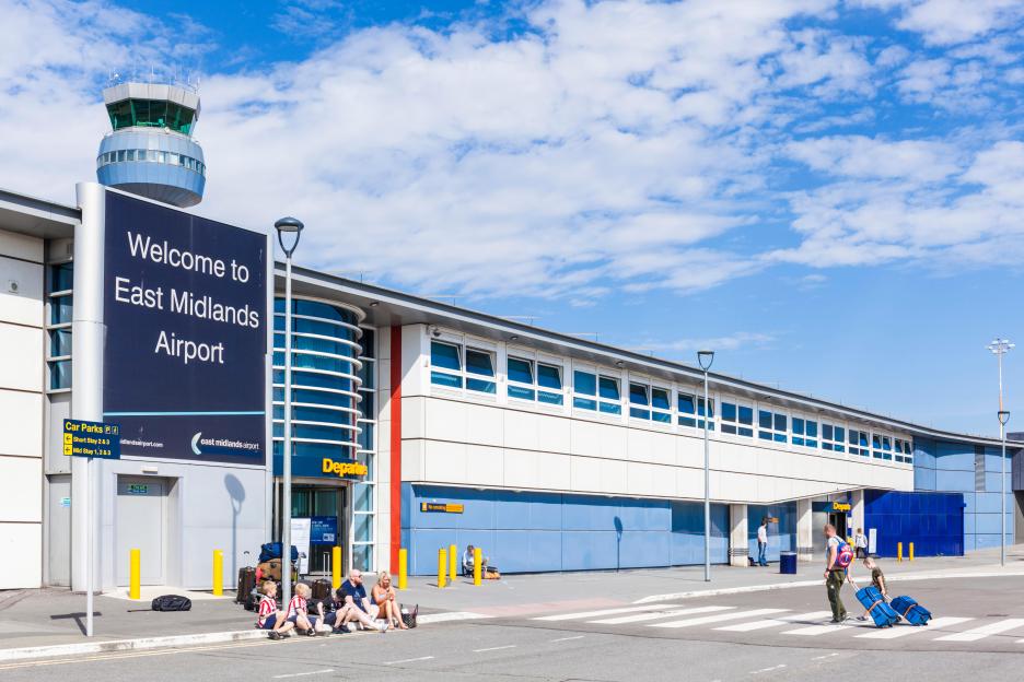 East Midlands Airport terminal building with passengers and the air traffic control tower.
