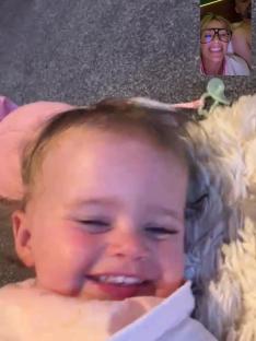 Baby smiling during a video call with a woman.